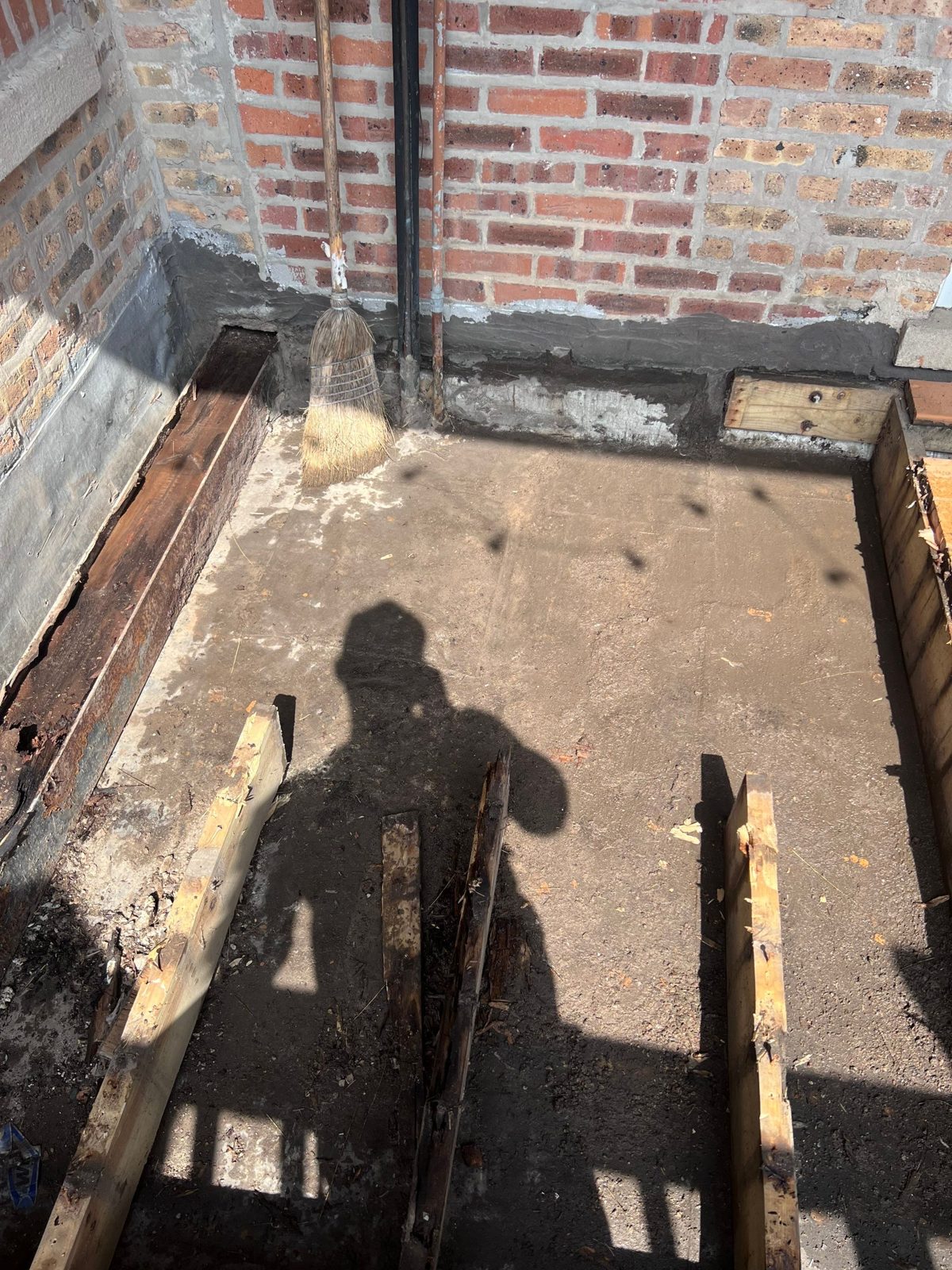 Base prep and framing at brick-wall interface for concrete work.
