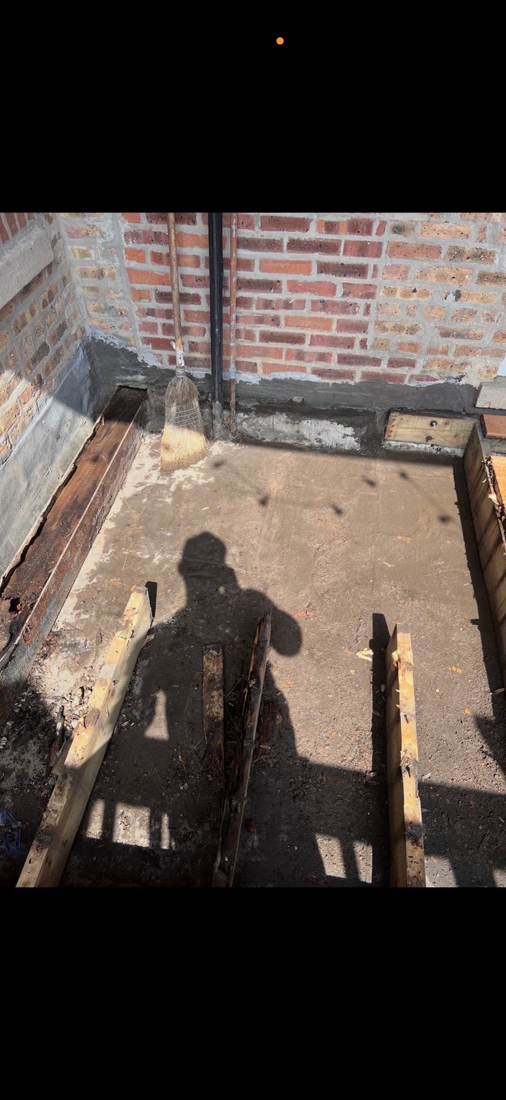 Base prep and framing at brick wall for concrete slab work.