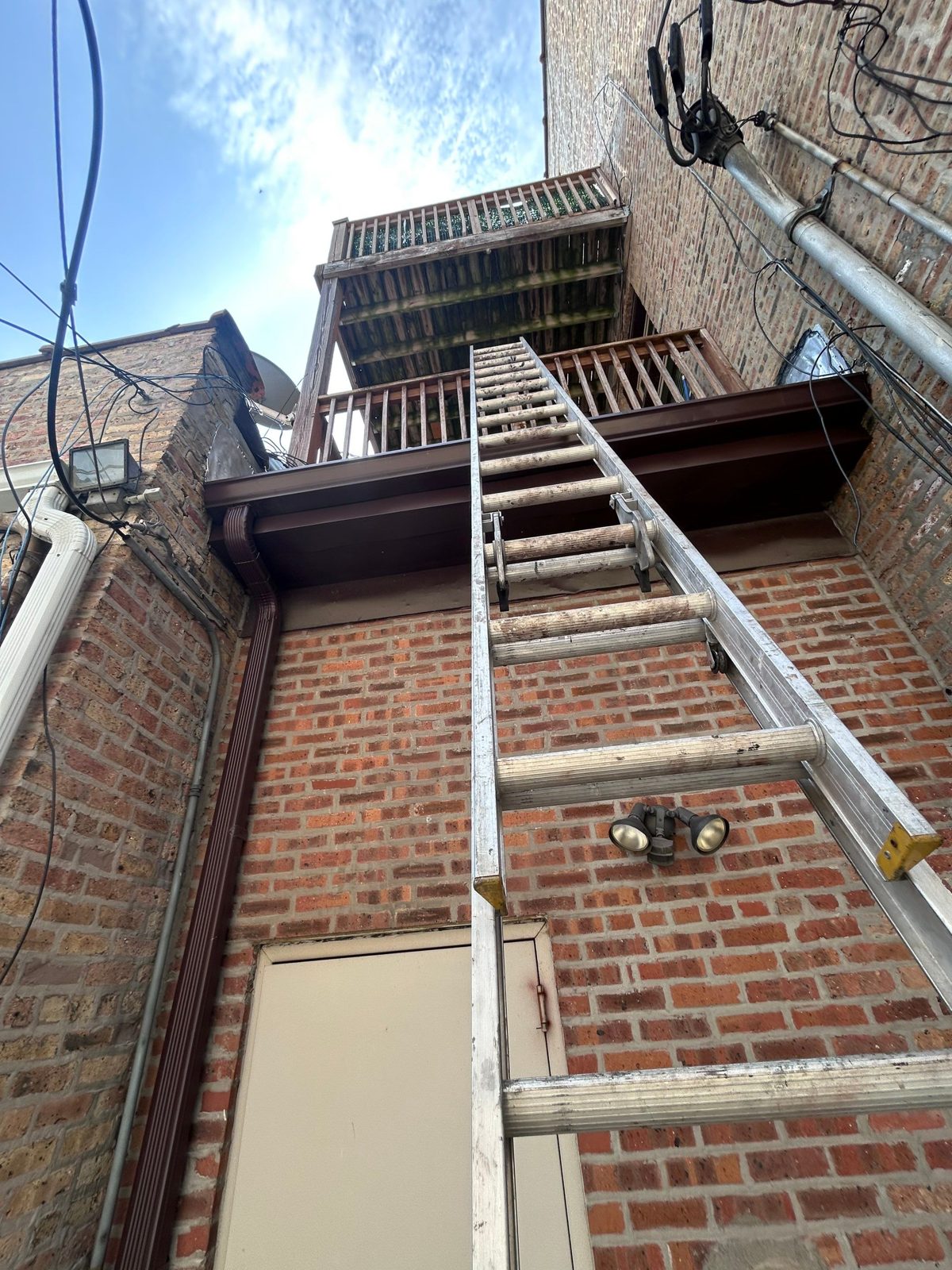 Gutter and downspout interface on a multi-story brick facade.