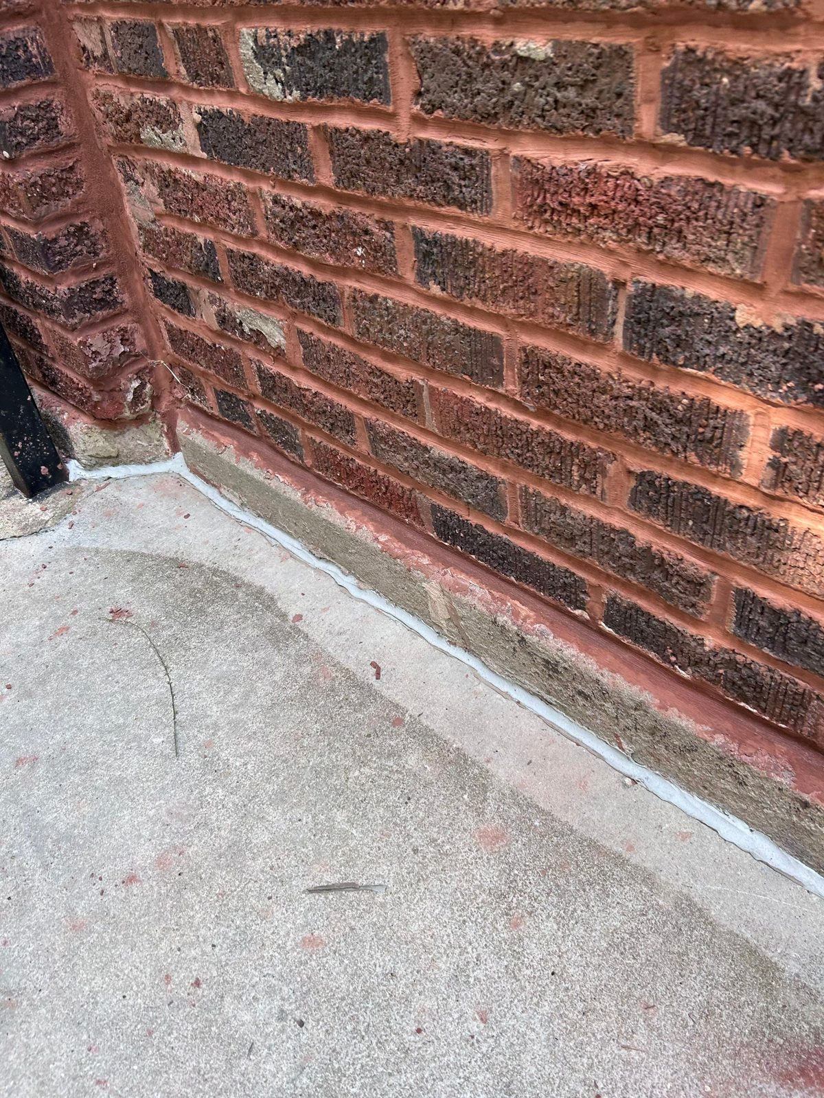 Fresh sealant joint where brick masonry meets the concrete walkway.