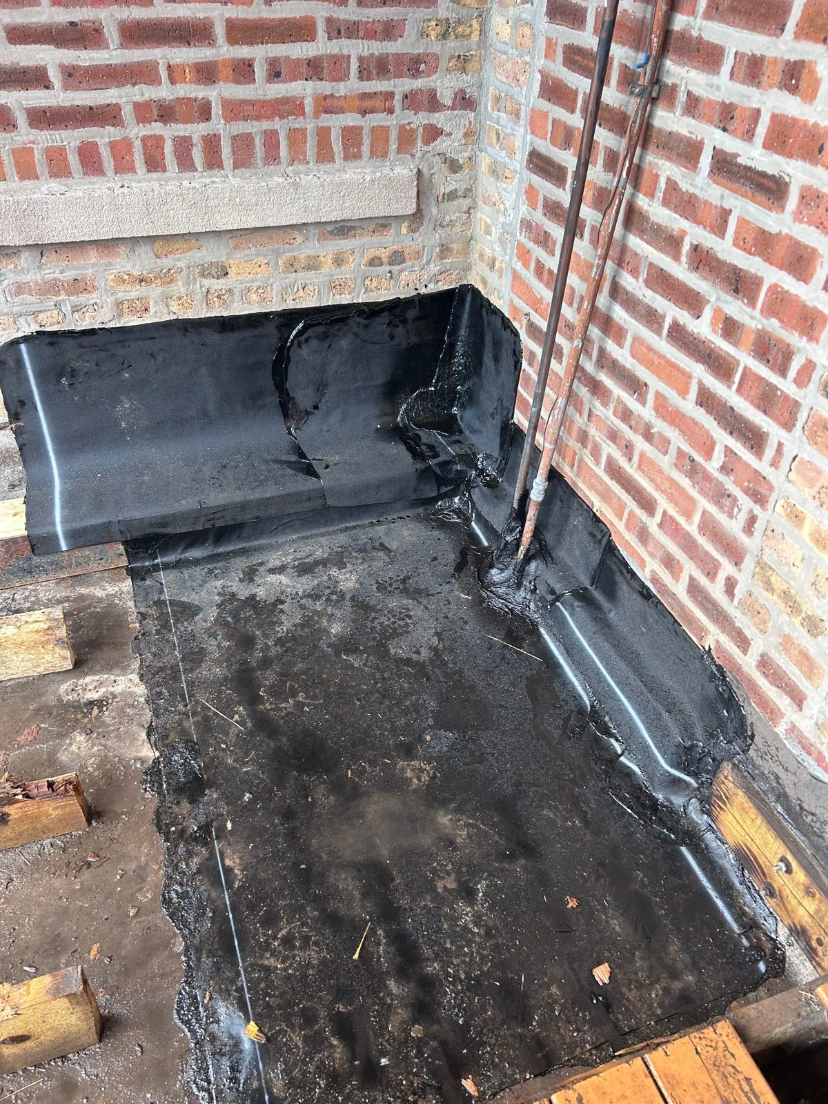 Waterproofing membrane at a brick-wall corner during exterior repair.