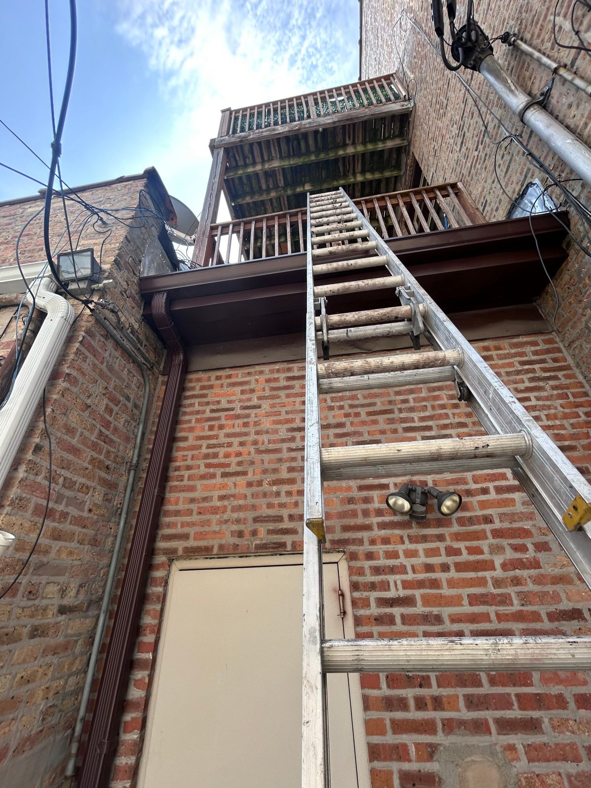 Ladder access to brick facade with gutter and downspout.