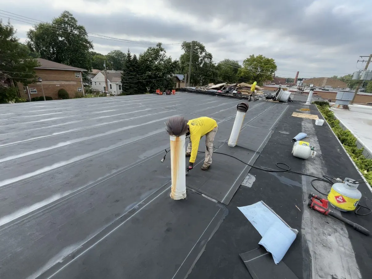 Crew torching a modified bitumen membrane on a flat roof.