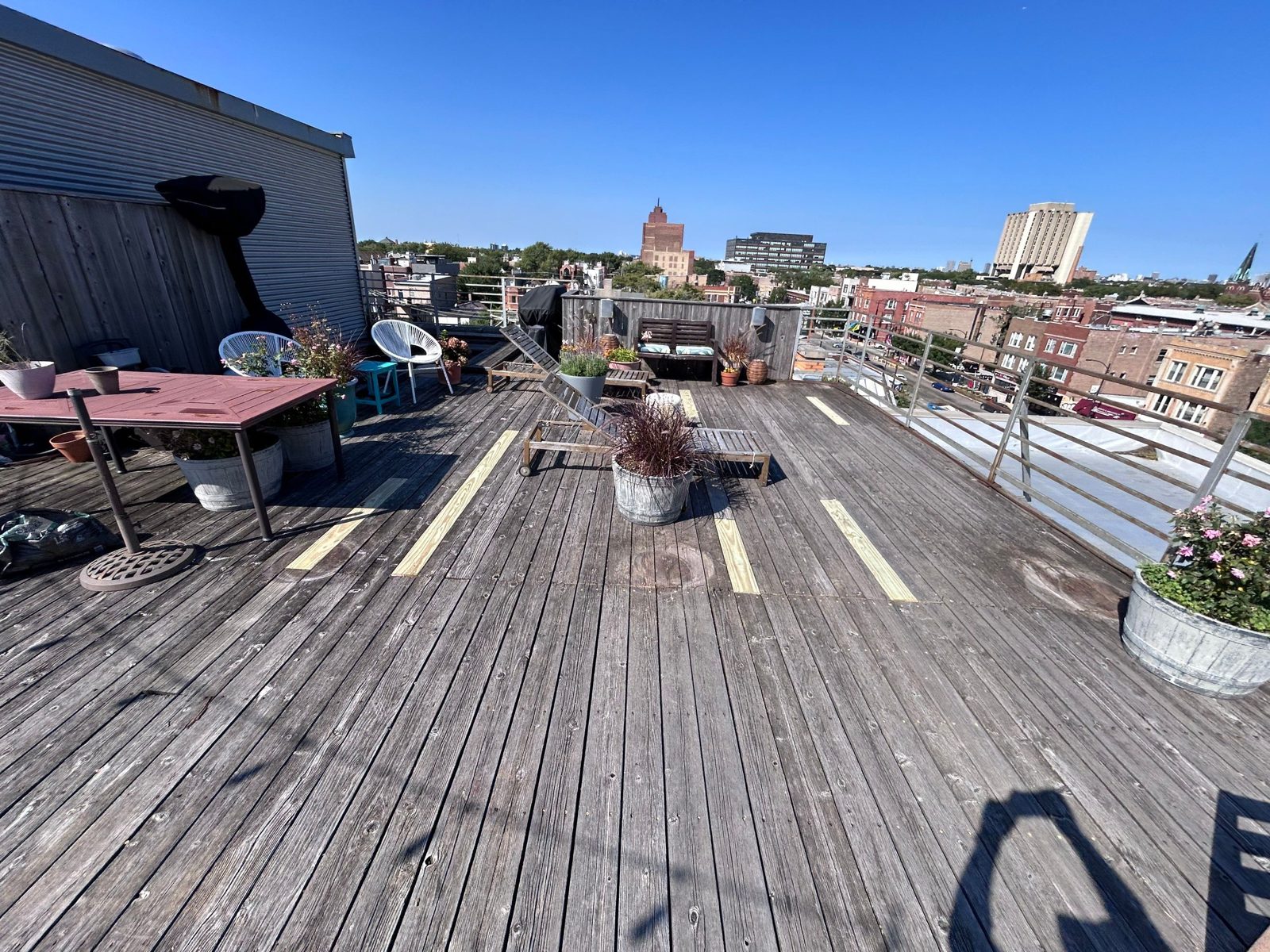 Wide rooftop living space showing deck board replacement in progress.