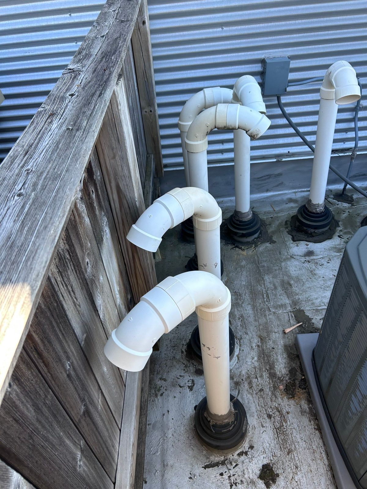 Flat-roof PVC vents sealed with rubberized flashing and gooseneck caps.