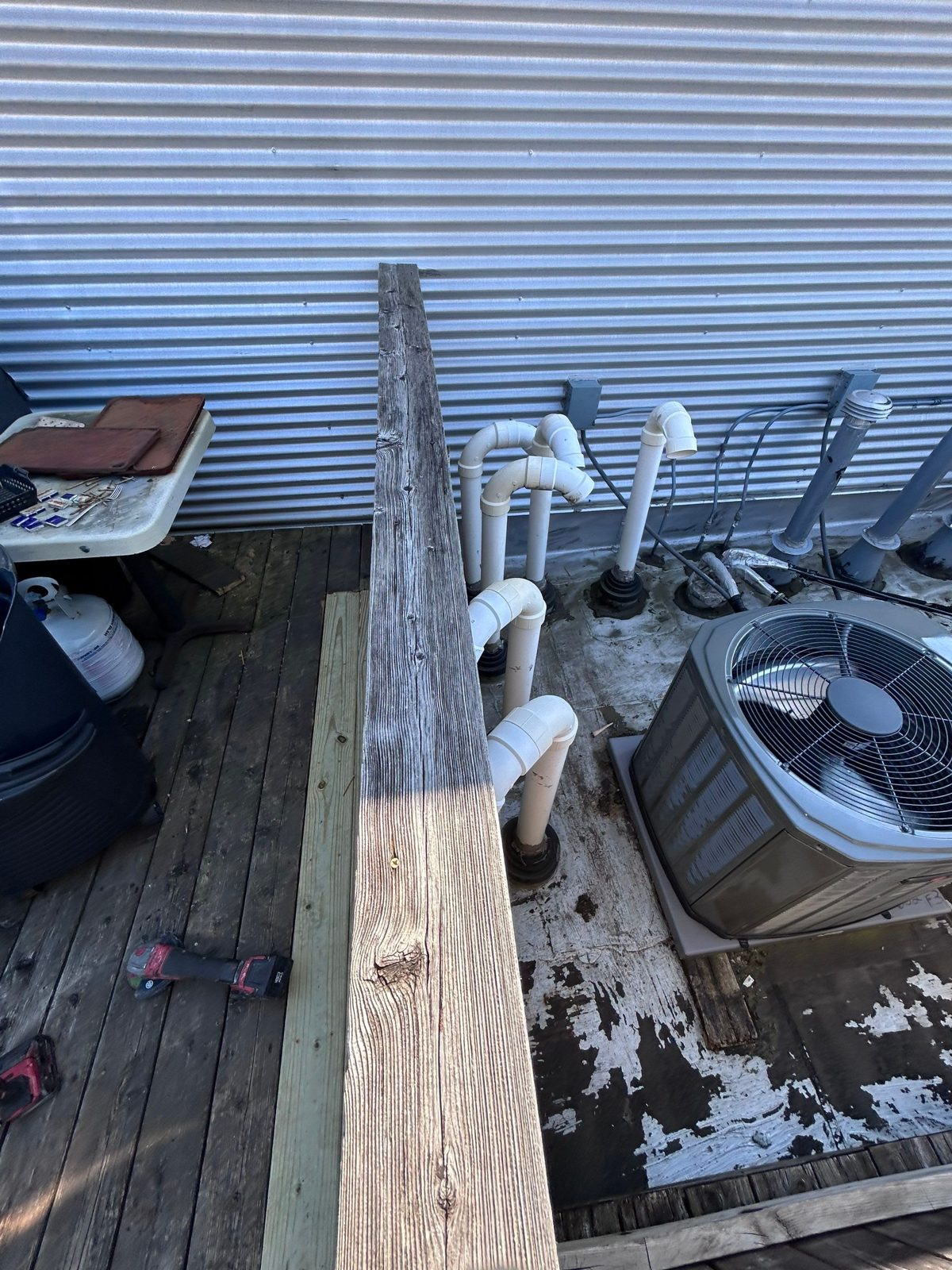 Flat membrane roof with peeling coating, penetrations, and HVAC unit.