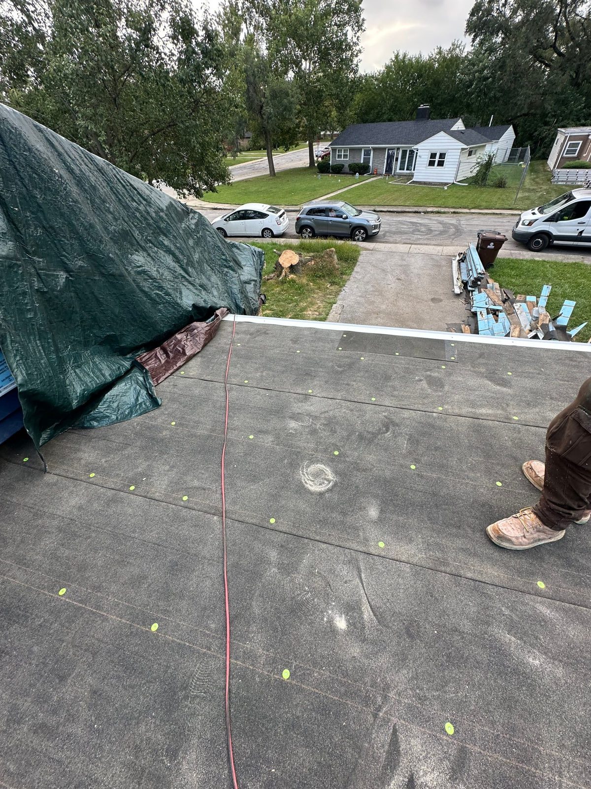 Black underlayment fastened with green cap nails on a residential flat roof.