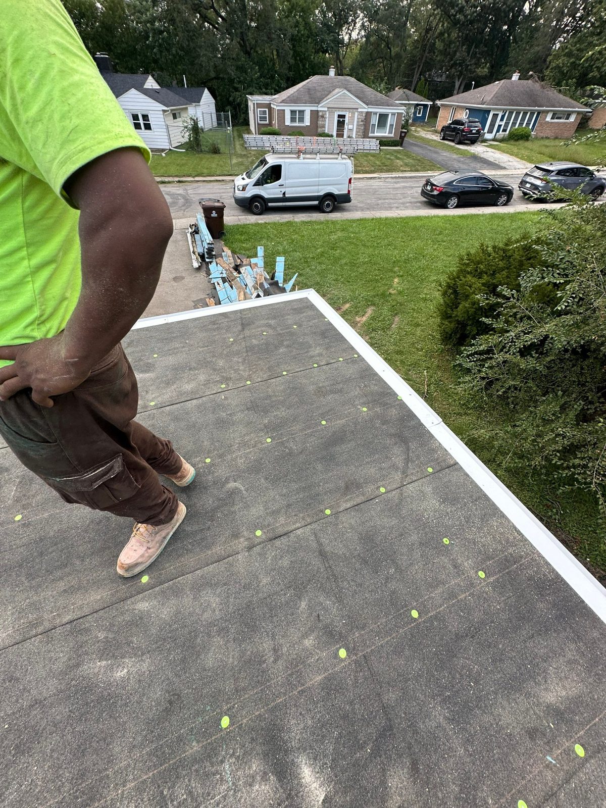 Crew installing flat-roof underlayment and white drip-edge flashing.