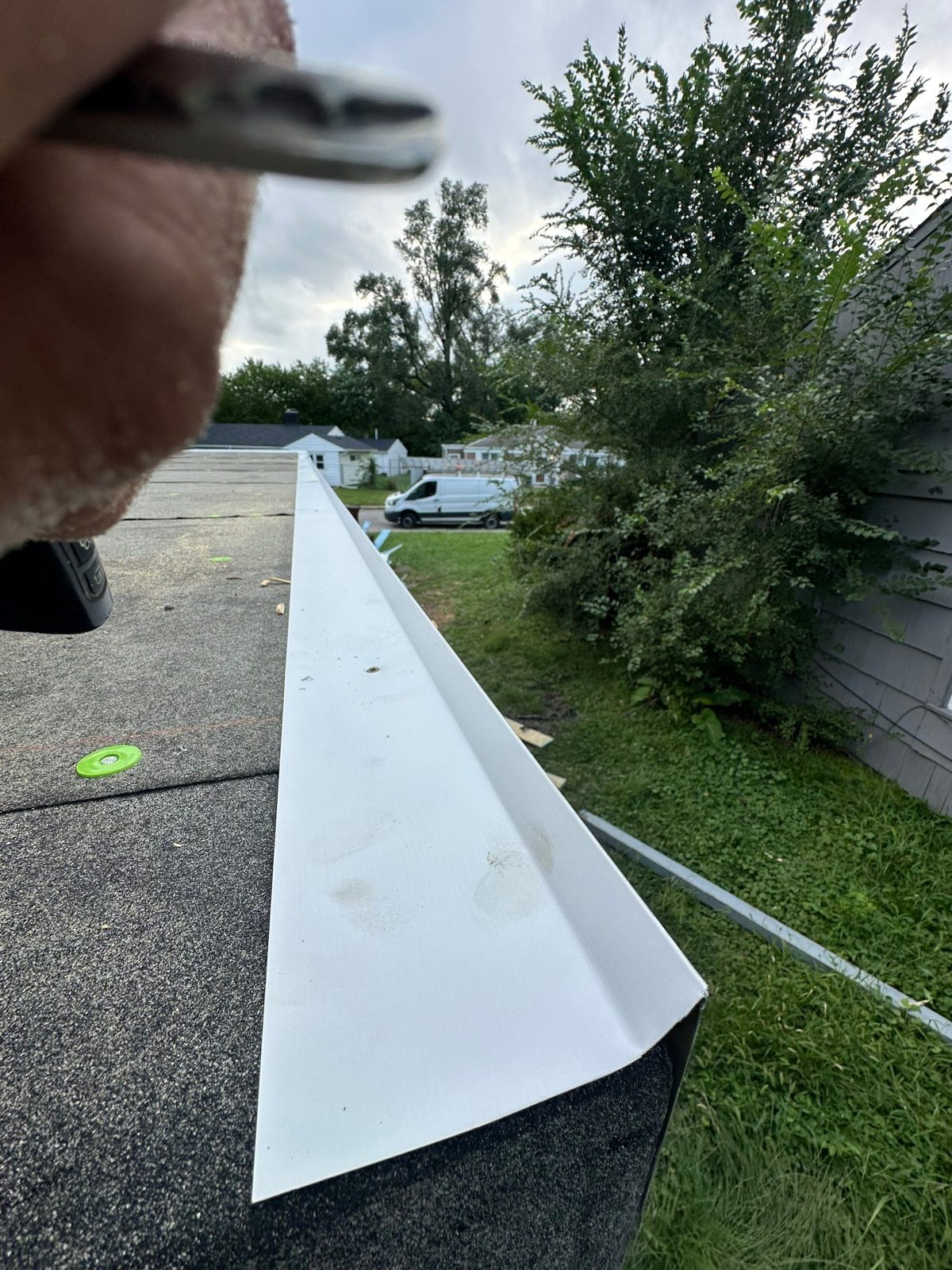 Close-up of white metal drip edge on granular flat-roof membrane.