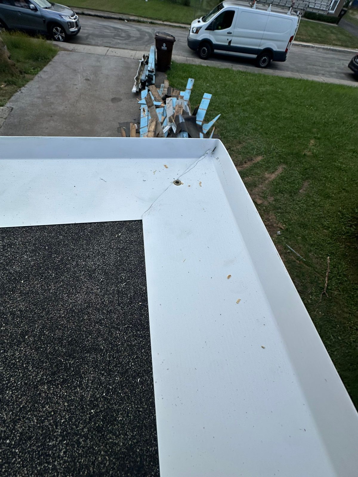 Mitered white corner flashing detail on dark asphalt roof surface.